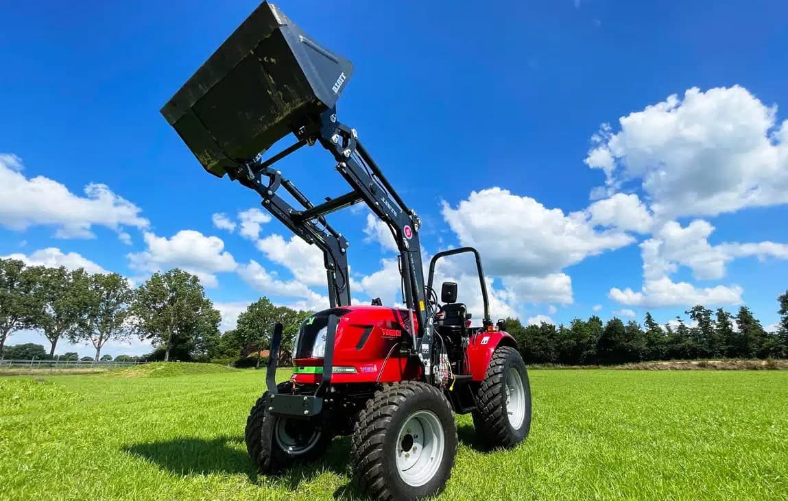 Elektrischer Traktor mit Frontlader auf einer Grasfläche